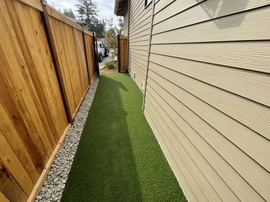 synthetic turf edge with river rock border installed in small backyard in Bellevue, WA.