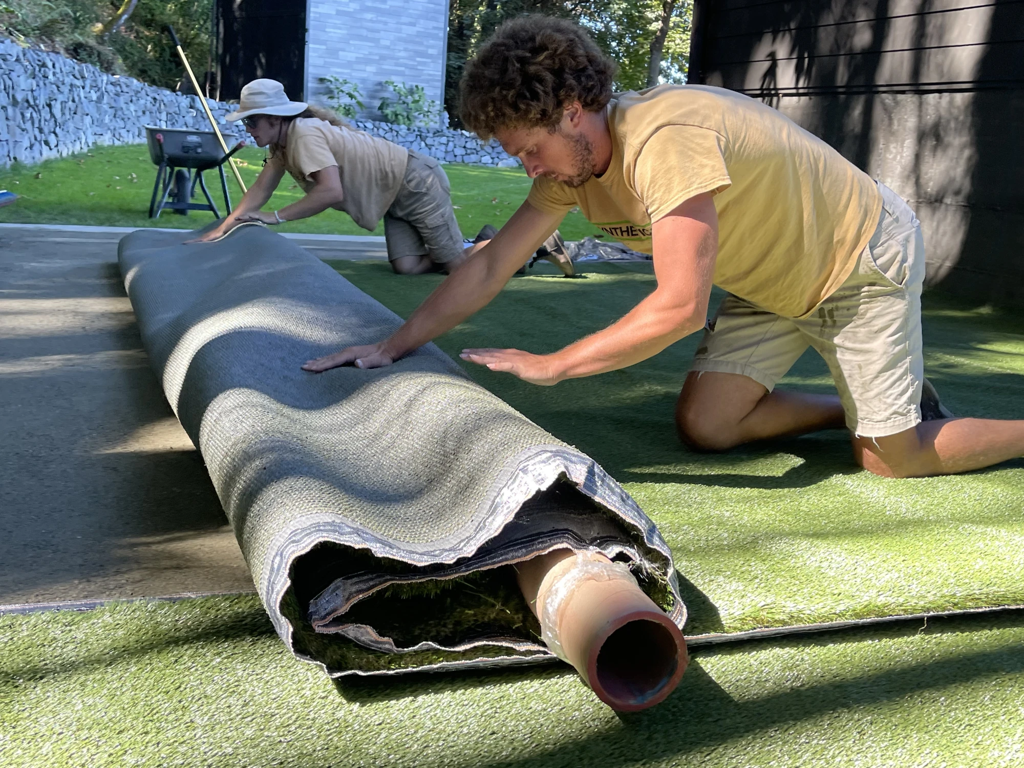 Artificial grass installation team carefully unrolls roll of fake grass at customers house