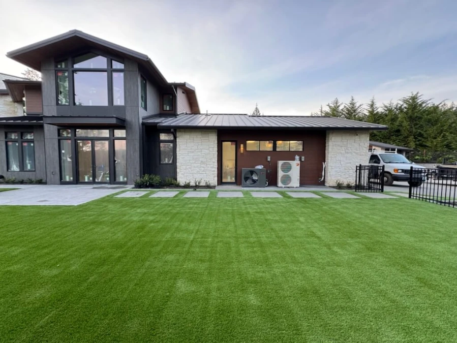View of large-scale backyard artificial turf installation in Gig Harbor showing invisible professional seam work and pavers